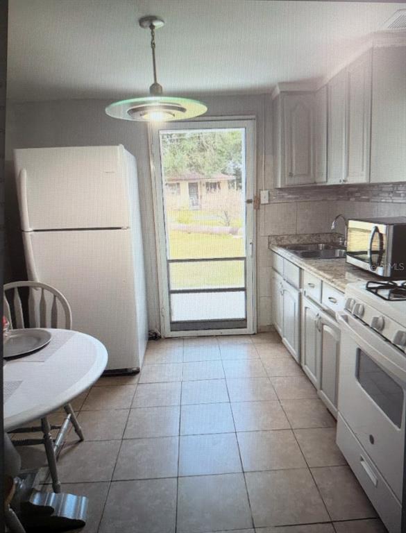 A kitchen with white cabinets, a white refrigerator, a gas stove, and a glass-paned door — 2725 SAMPLE STREET, KISSIMMEE, FL