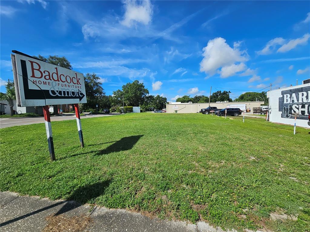 A vacant grass lot features a Badcock Home Furniture sign and a partial building sign — 0 GALL BOULEVARD, ZEPHYRHILLS, FL