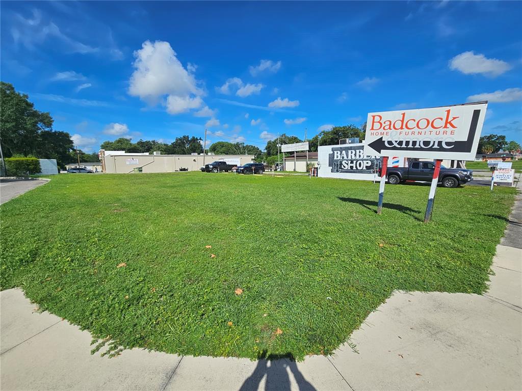 A vacant grassy lot features a large commercial sign and a nearby building — 0 GALL BOULEVARD, ZEPHYRHILLS, FL