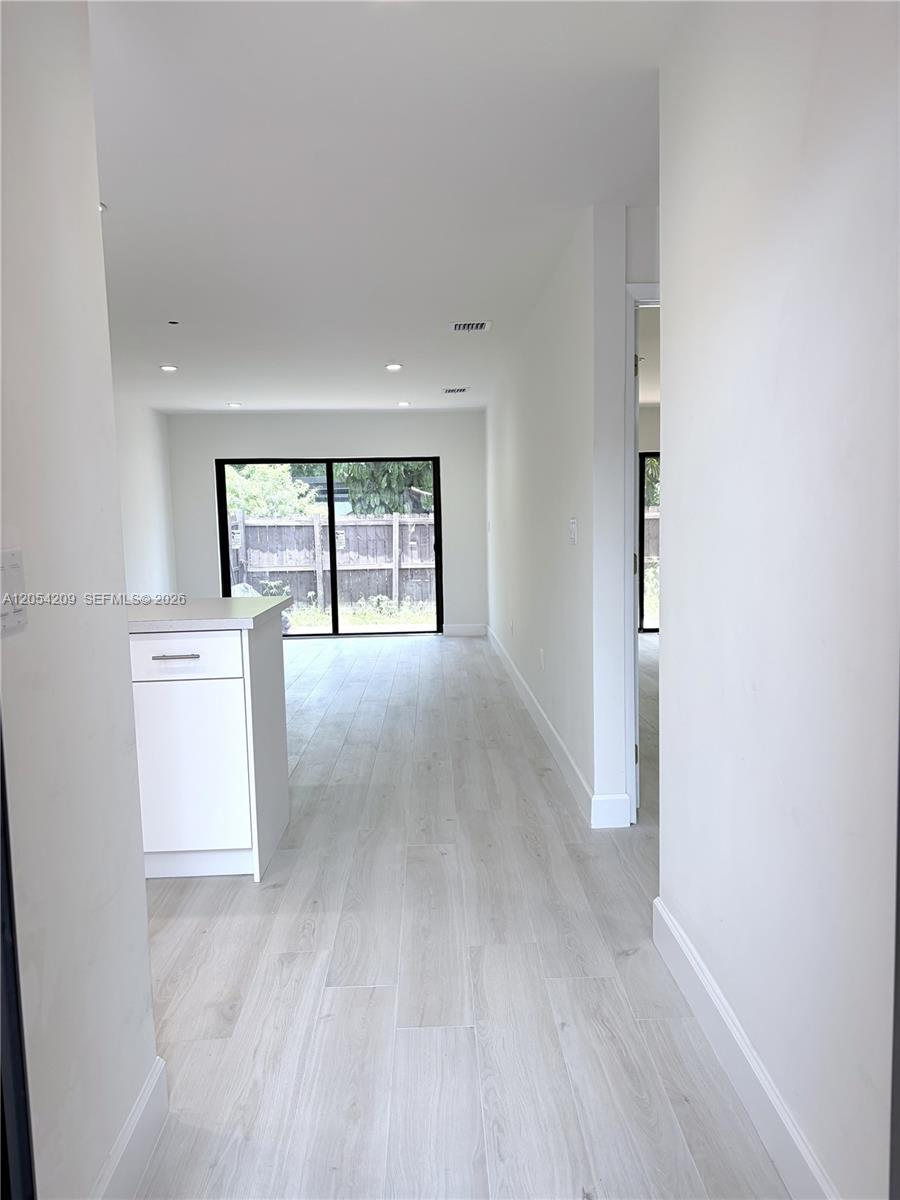 A white kitchen island sits in a hallway leading to a room with sliding doors — 3809 SW 82nd Ave # 20, Miami FL 33155, MIAMI, FL