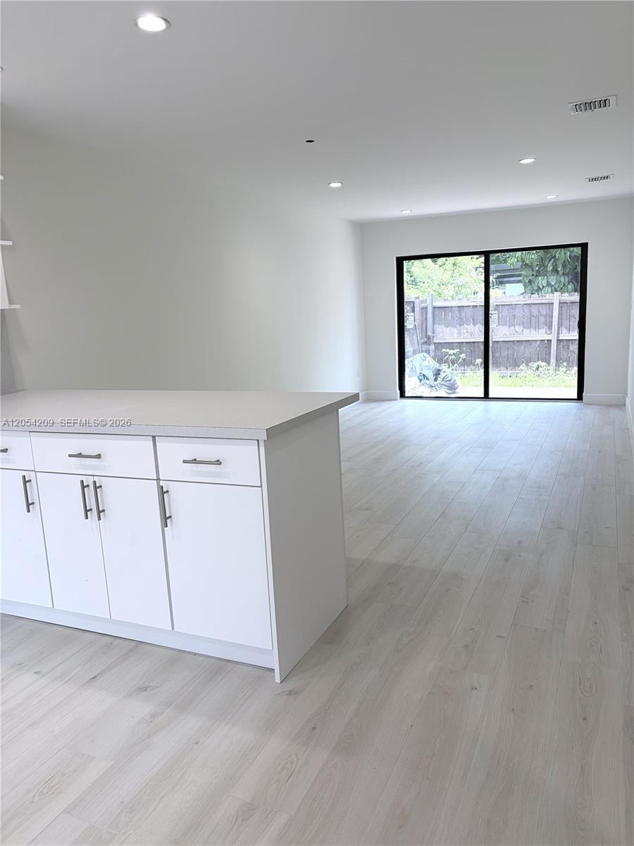 A white kitchen island sits in a room with light wood-look flooring and sliding doors — 3809 SW 82nd Ave # 20, Miami FL 33155, MIAMI, FL