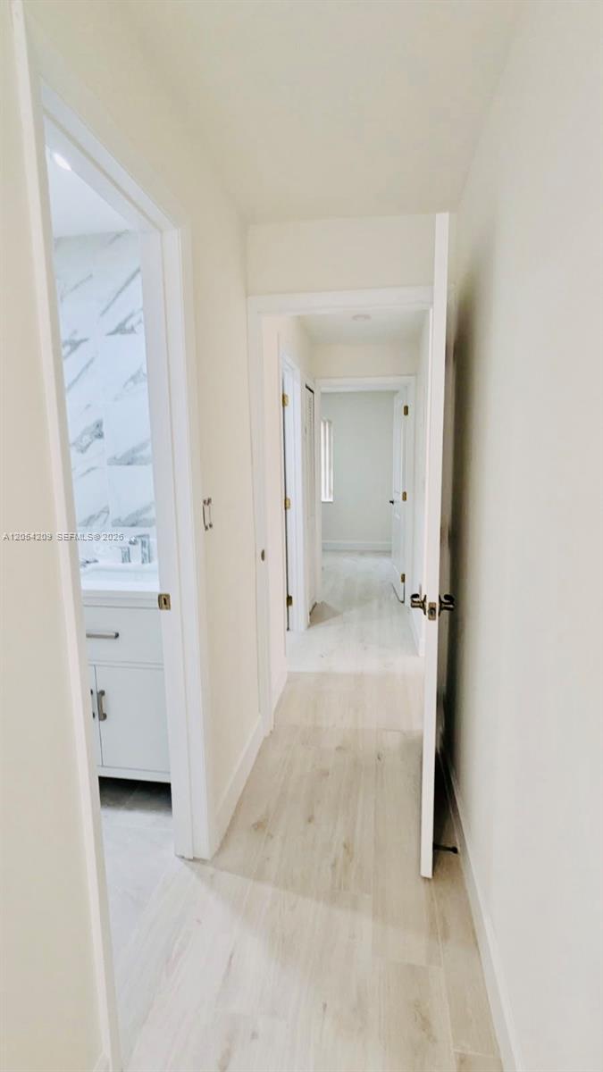 A hallway with light wood-look flooring leads to a bathroom and a bedroom — 3809 SW 82nd Ave # 20, Miami FL 33155, MIAMI, FL
