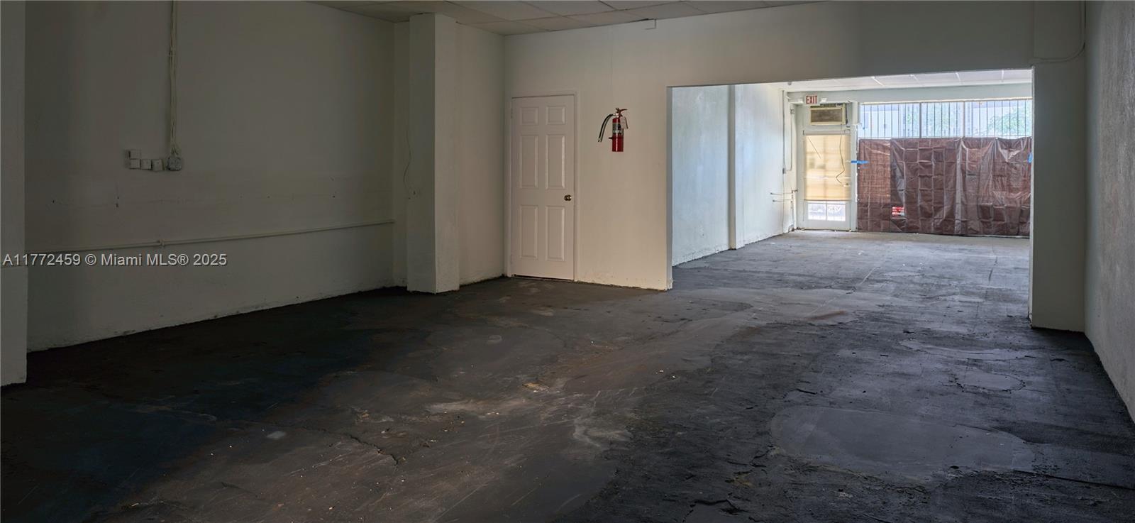 An empty commercial space features white walls, a dark concrete floor, and a fire extinguisher — 6211 NW 7th Ave # 663, Miami FL 33150, MIAMI, FL