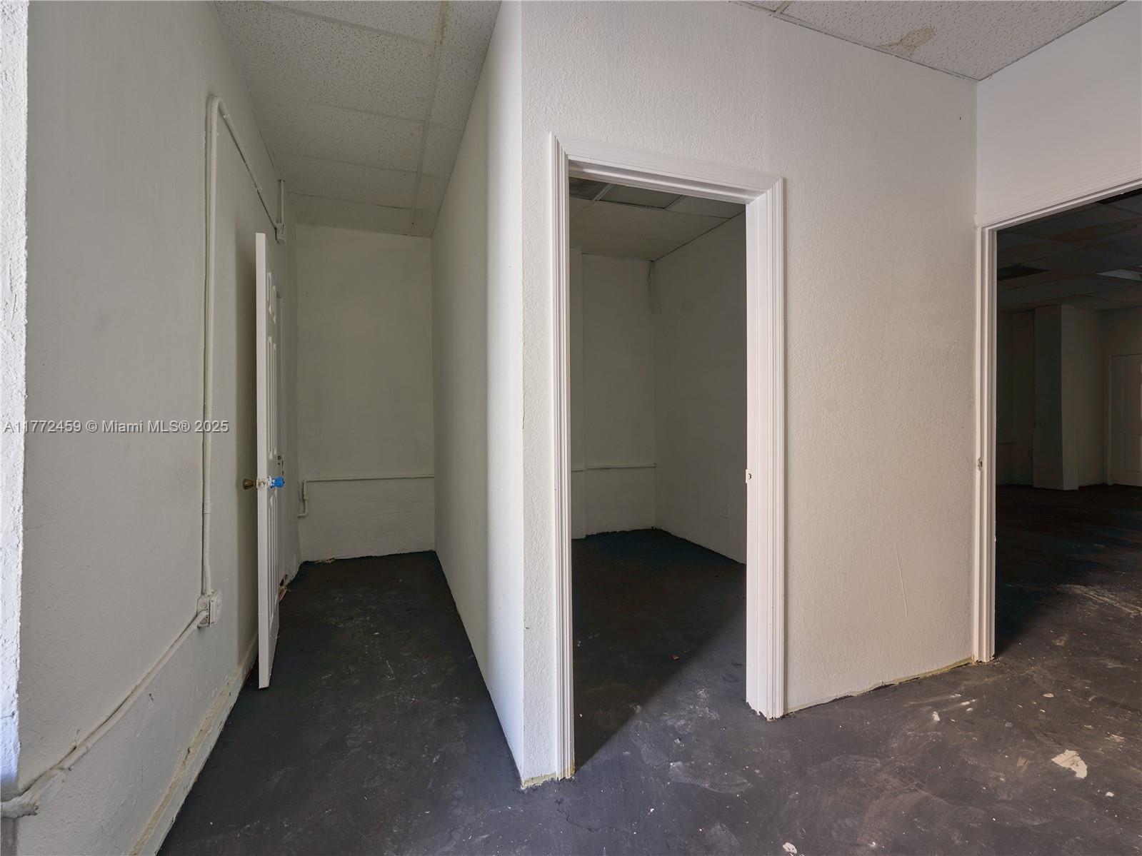 An interior view shows three doorways leading into small, unfinished rooms with dark concrete floors — 6211 NW 7th Ave # 663, Miami FL 33150, MIAMI, FL