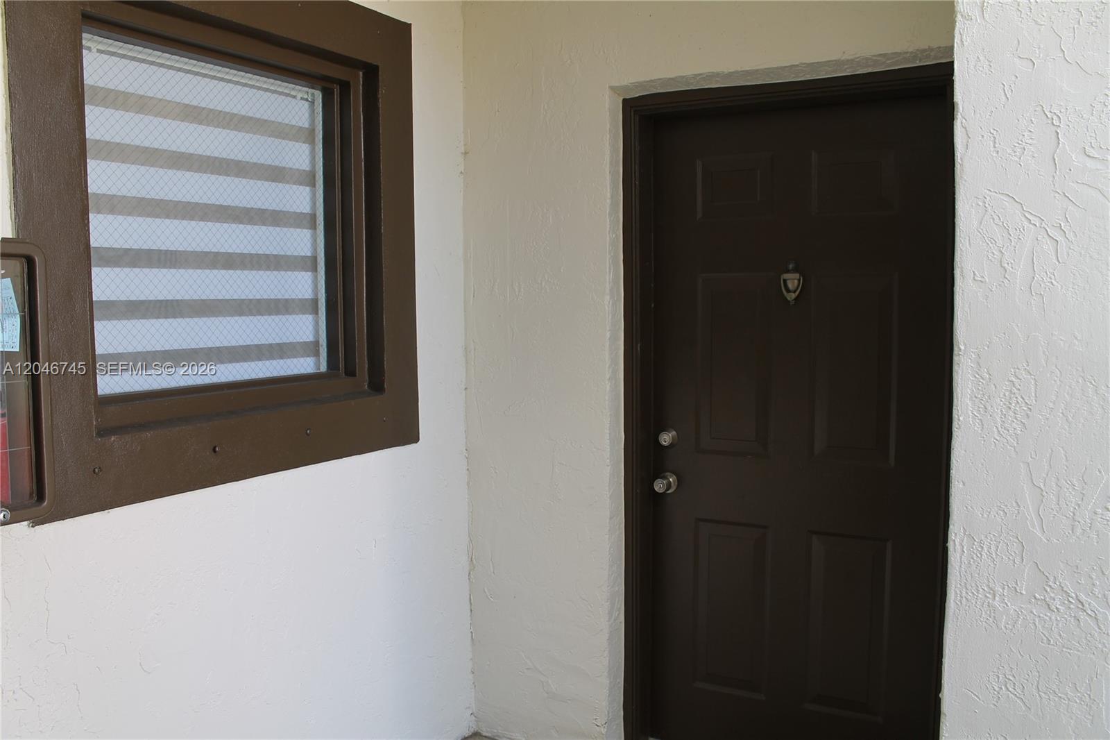 A dark brown door and a matching window frame are set against a white wall — 1153 NW 125th Pl # 106, Miami FL 33182, MIAMI, FL