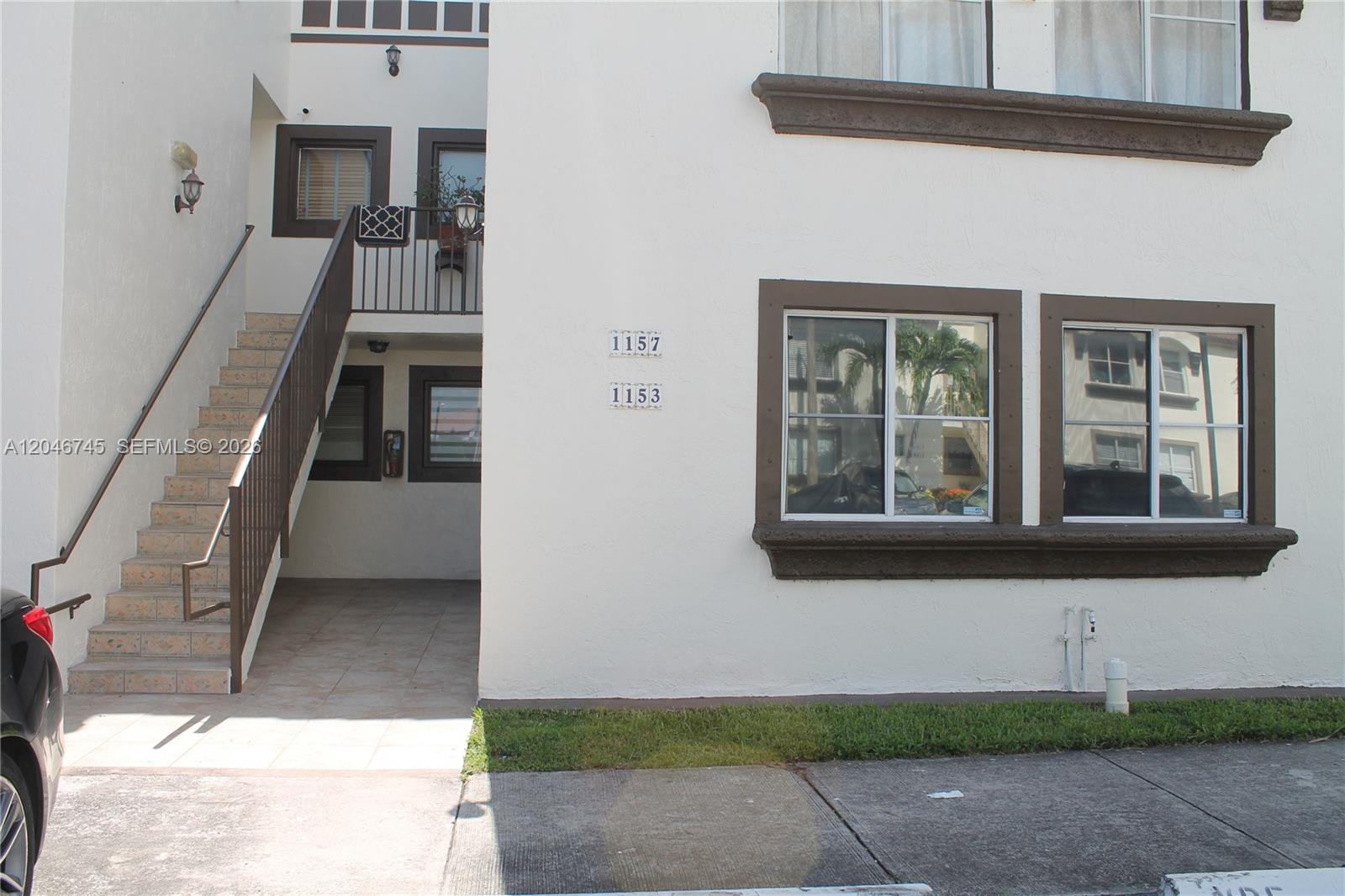 The exterior of a multi-story building features a staircase, windows with brown trim, and unit numbers — 1153 NW 125th Pl # 106, Miami FL 33182, MIAMI, FL