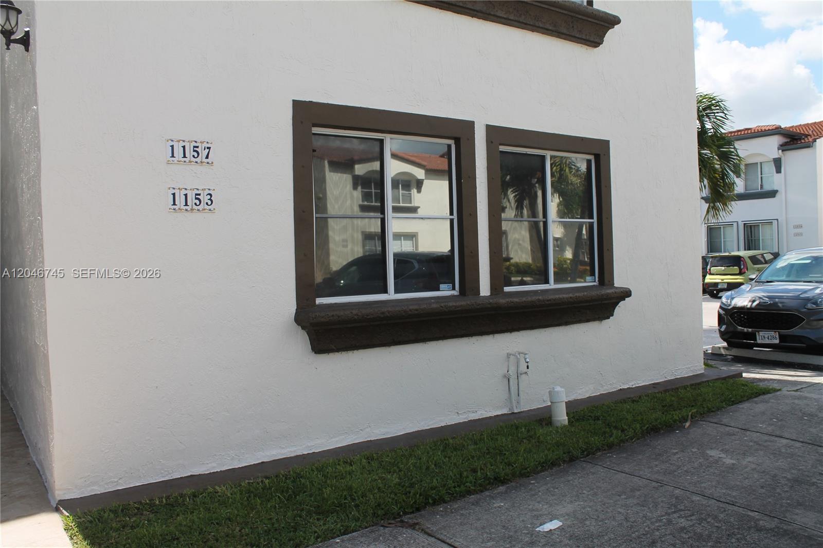 The exterior of a white stucco building features two windows with dark brown trim — 1153 NW 125th Pl # 106, Miami FL 33182, MIAMI, FL