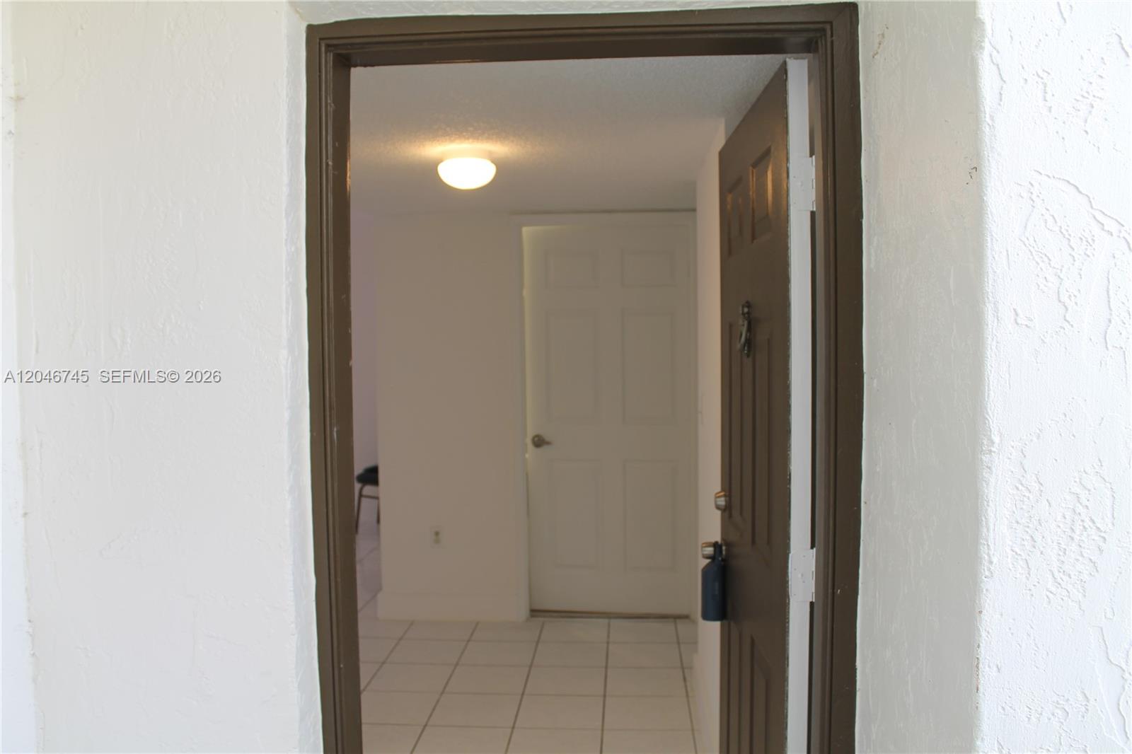 A view through an open doorway shows a tiled entryway with a white door — 1153 NW 125th Pl # 106, Miami FL 33182, MIAMI, FL