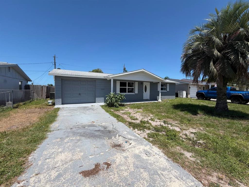 A single-story gray house with a garage, a concrete driveway, and a palm tree — 3511 CAMBRIDGE STREET, NEW PORT RICHEY, FL