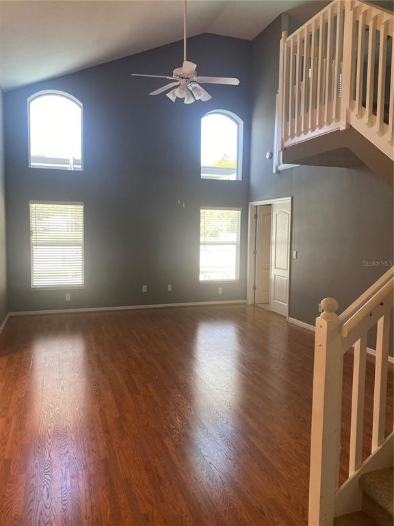 A living room with high ceilings, dark gray walls, wood flooring, and a staircase — 10471 LUCAYA DRIVE, TAMPA, FL