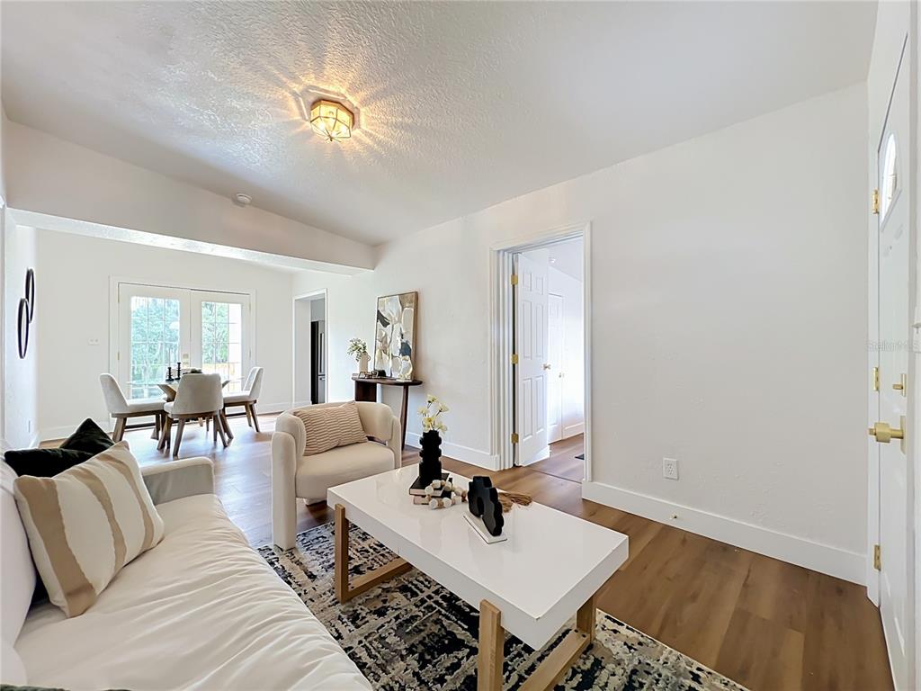 A living room features white walls, wood-look flooring, a white coffee table, and dining area — 3828 WHITE HERON DRIVE, ORLANDO, FL
