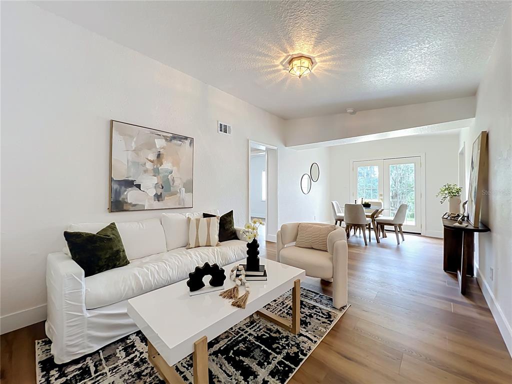 A living room with a white sofa, coffee table, and an adjacent dining area — 3828 WHITE HERON DRIVE, ORLANDO, FL
