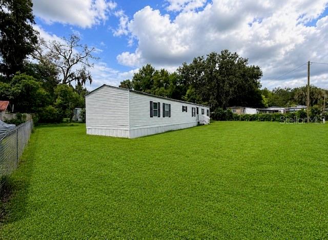 A white mobile home sits on a large, grassy lot under a cloudy sky — 3464 SE 91ST PLACE, OCALA, FL