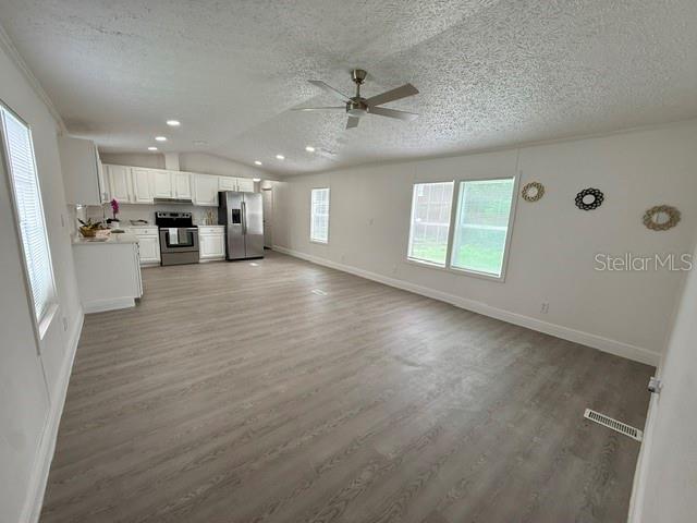 An open-concept kitchen and living area features white cabinetry, stainless steel appliances, and wood flooring — 3464 SE 91ST PLACE, OCALA, FL