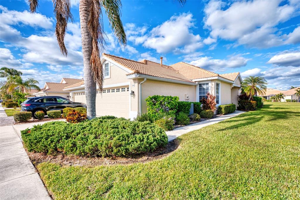 A beige single-story house with a tile roof and a two-car garage — 4980 WHISPERING OAKS DRIVE, NORTH PORT, FL