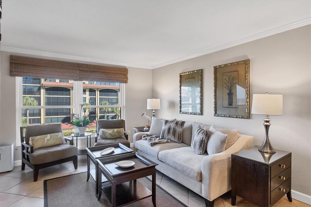 A living room features a beige sofa, two armchairs, nested coffee tables, and framed artwork — 8750 MIDNIGHT PASS ROAD UNIT 302, SARASOTA, FL