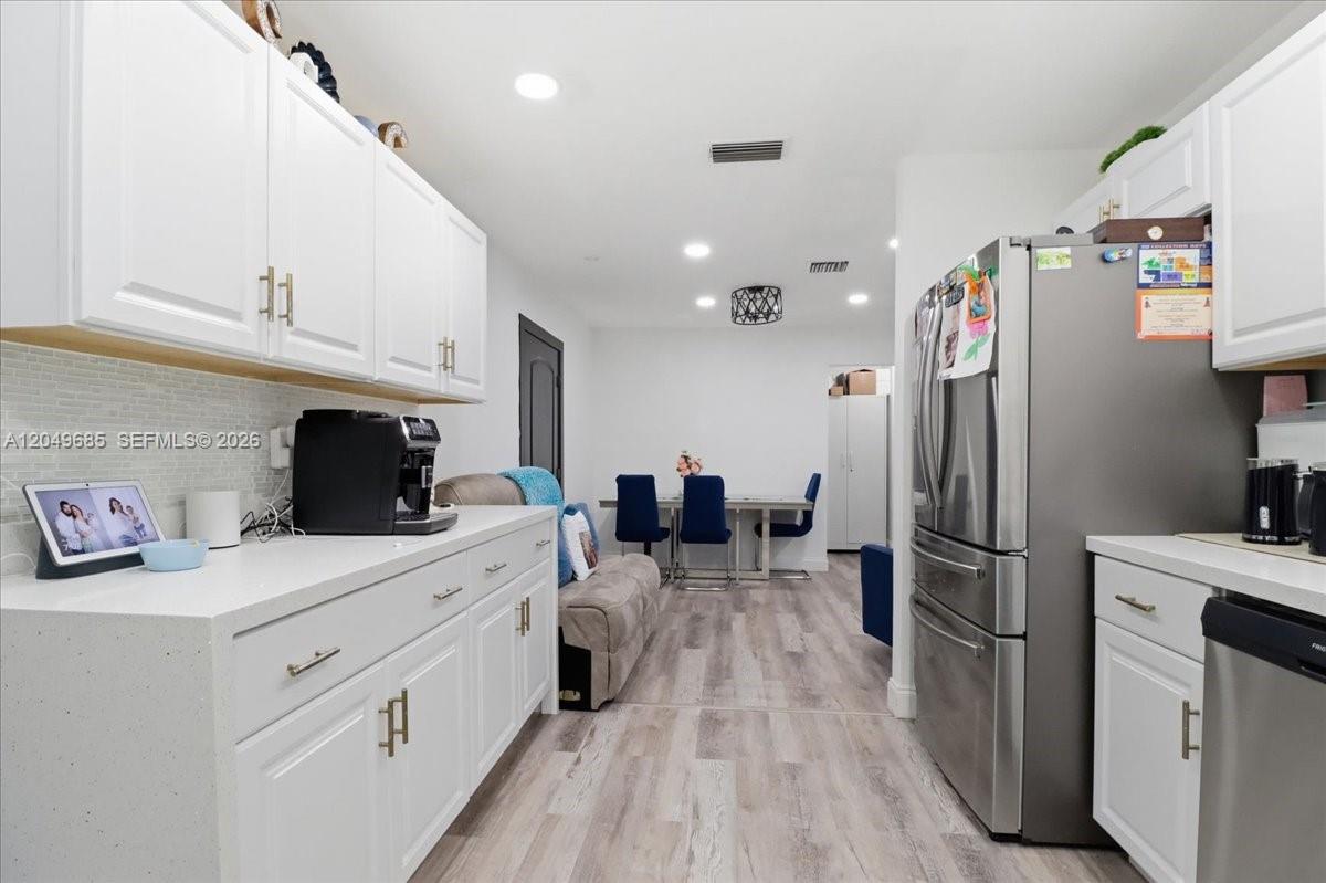 A kitchen with white cabinets, stainless steel appliances, and light wood-look flooring — 7551 Polk St, Hollywood FL 33024, HOLLYWOOD, FL