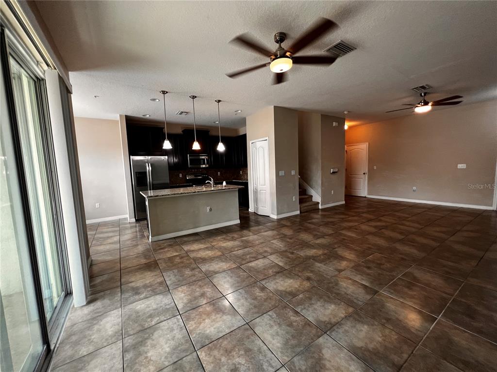 An open-concept kitchen with dark cabinets and an island overlooks a tiled living area — 8613 ANDALUCIA FIELD DRIVE, TAMPA, FL