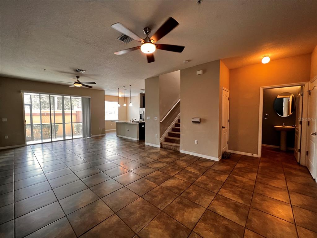 An open-concept living area features tile flooring, a ceiling fan, and a kitchen with island — 8613 ANDALUCIA FIELD DRIVE, TAMPA, FL