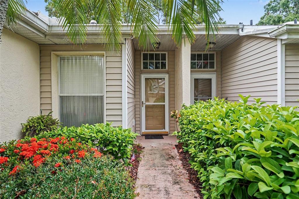 A concrete walkway leads to the front entrance of a house with beige siding — 2437 NANTUCKET HARBOR LOOP UNIT 2437, SUN CITY CENTER, FL