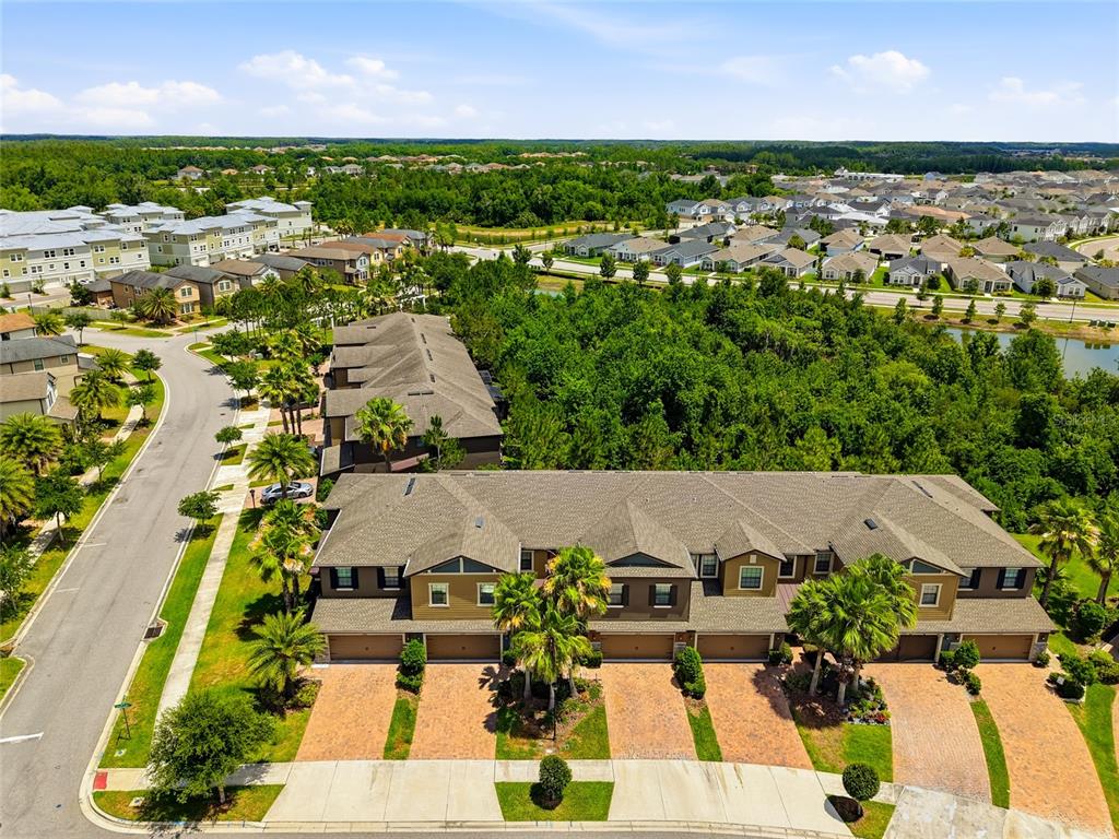 An aerial view shows a multi-unit townhouse complex with attached garages and brick-paved driveways — 28580 TRANQUIL LAKE CIRCLE, WESLEY CHAPEL, FL