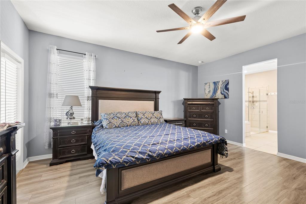 A bedroom features a dark wood bed frame, matching nightstands, a dresser, and light wood flooring — 12015 STONE BARK TRAIL, ORLANDO, FL