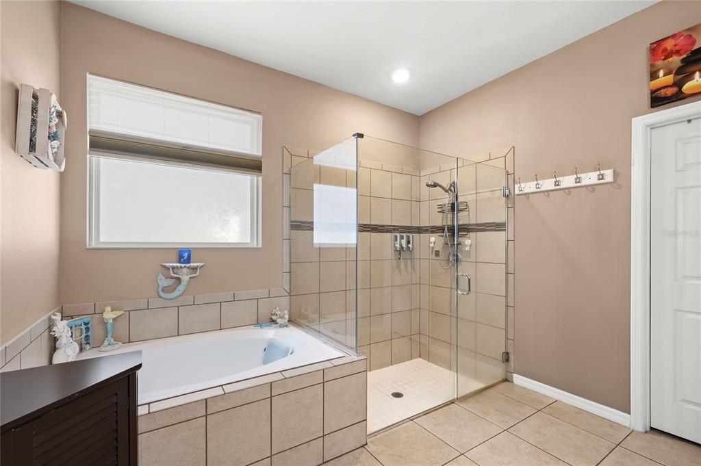 A bathroom features a tiled soaking tub, a glass-enclosed walk-in shower, and tan walls — 12015 STONE BARK TRAIL, ORLANDO, FL