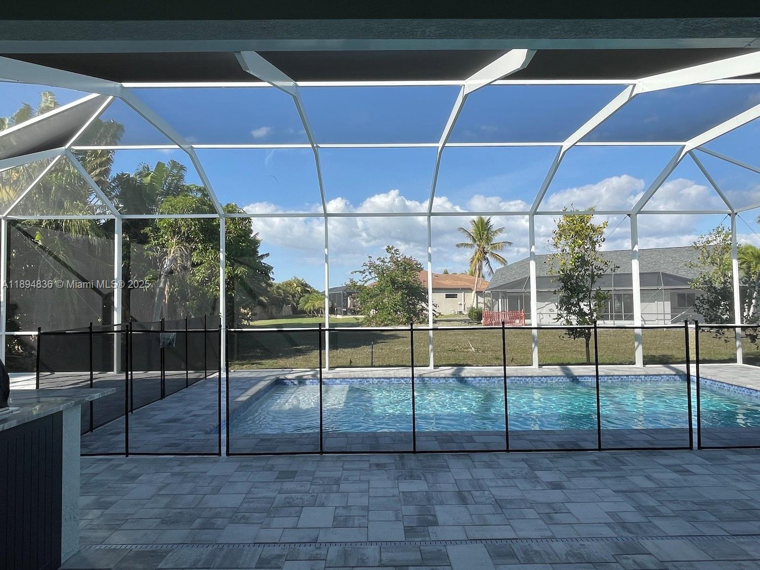 A swimming pool with a safety fence is enclosed by a screened lanai — 2303 SW 43rd Ter, Cape Coral FL 33914, CAPE CORAL, FL