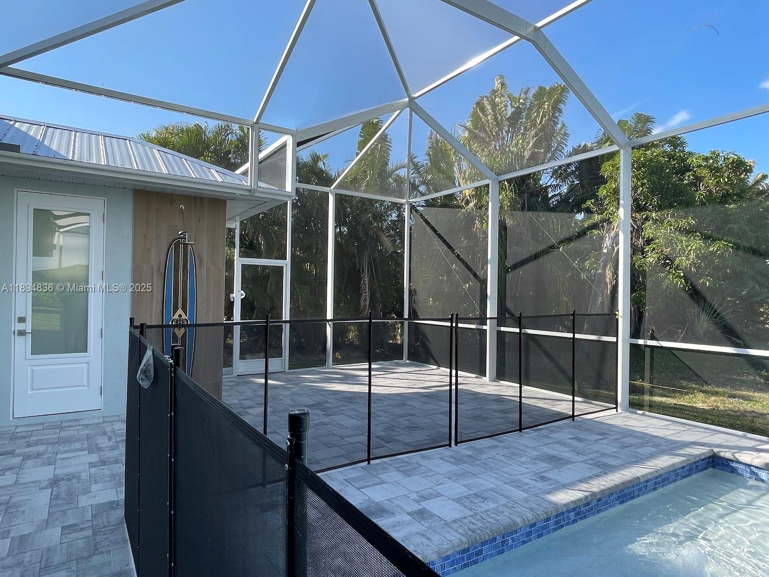A screened-in patio features a pool, paver flooring, and a black safety fence — 2303 SW 43rd Ter, Cape Coral FL 33914, CAPE CORAL, FL