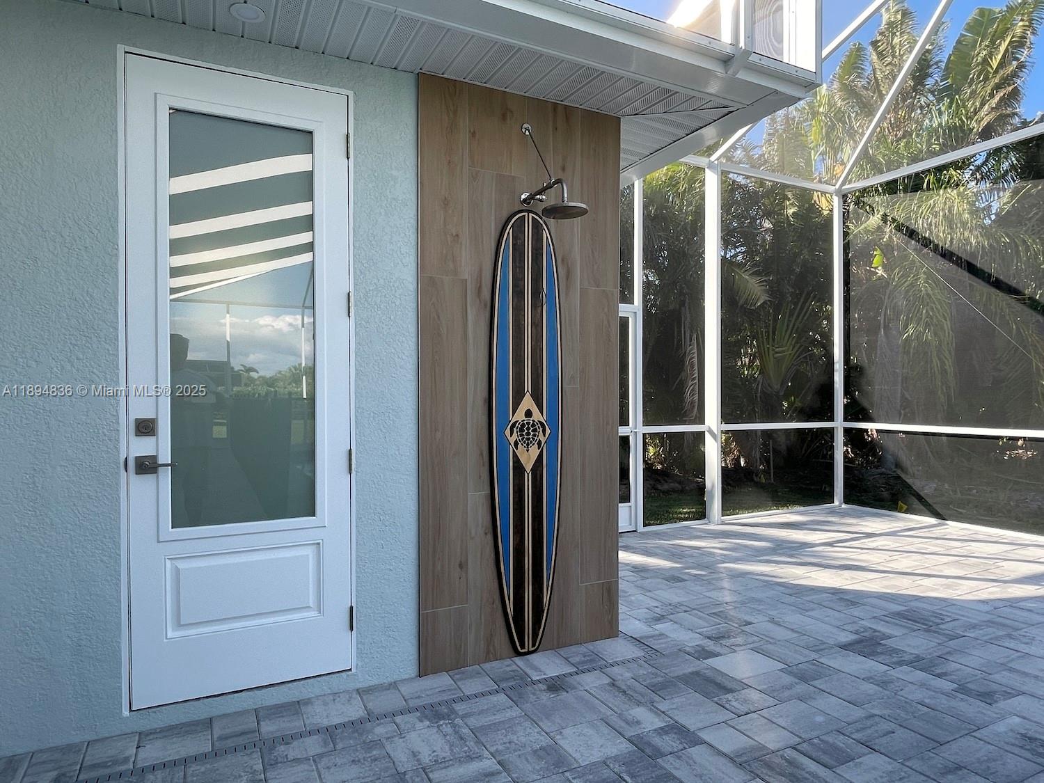 An outdoor shower features a surfboard-themed panel mounted on a wood-look tiled wall — 2303 SW 43rd Ter, Cape Coral FL 33914, CAPE CORAL, FL