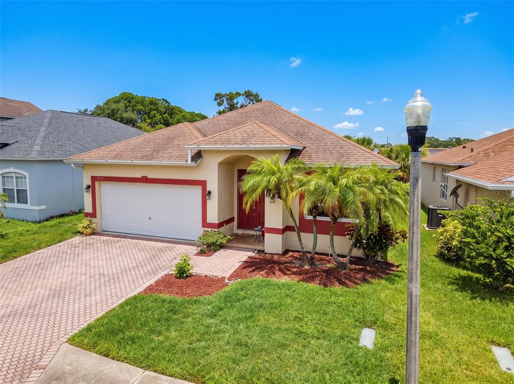 A single-story house with a tan stucco exterior, red trim, and a paved driveway — 9772 65TH WAY N, PINELLAS PARK, FL