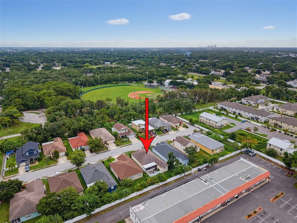An aerial view shows a residential house with a red arrow pointing to its roof — 9772 65TH WAY N, PINELLAS PARK, FL