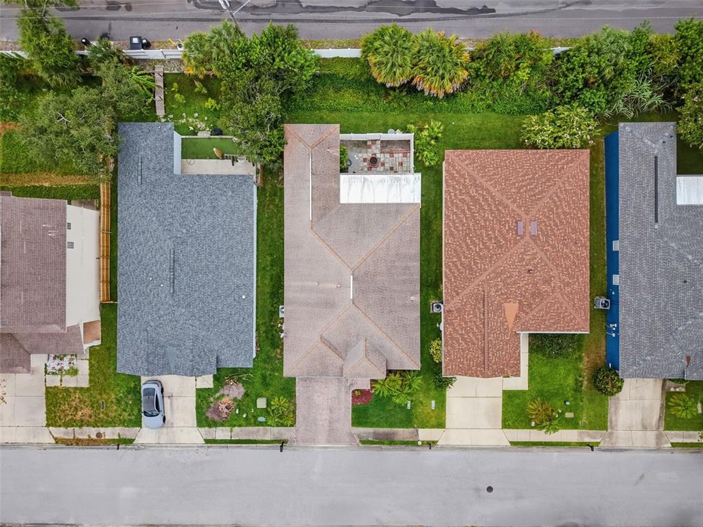 An aerial view shows three suburban houses with driveways and backyards along a paved street — 9772 65TH WAY N, PINELLAS PARK, FL