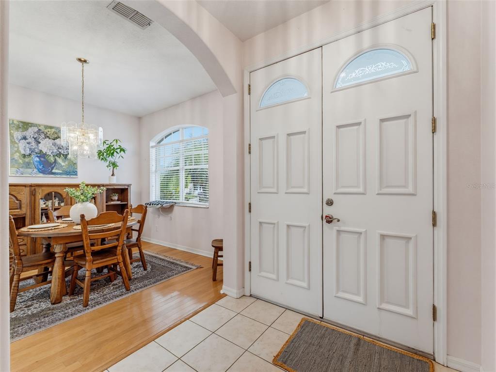 A tiled entryway leads to a dining room with hardwood floors and a wooden table — 9772 65TH WAY N, PINELLAS PARK, FL