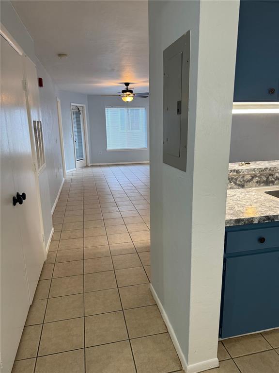 A hallway with tiled floors leads to a living area with a ceiling fan — 4000 SW 23RD STREET UNIT 1-106, GAINESVILLE, FL
