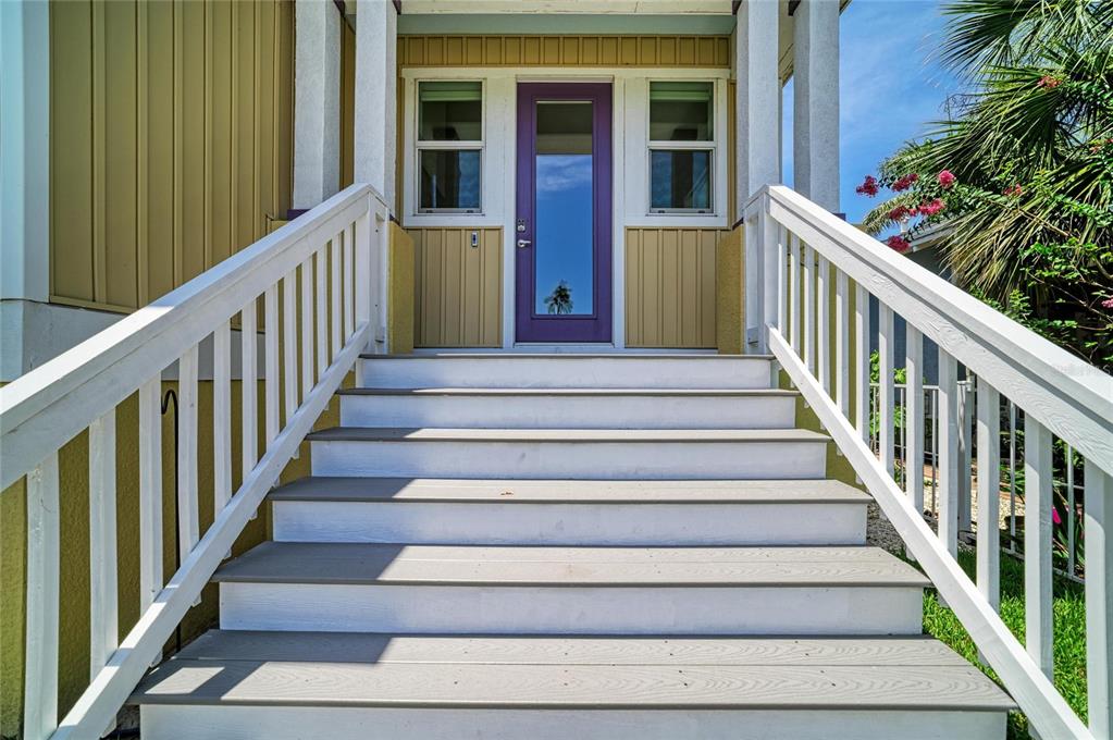 A set of wooden stairs leads up to a purple front door with white railings — 632 VIRGINIA DRIVE, BRADENTON, FL