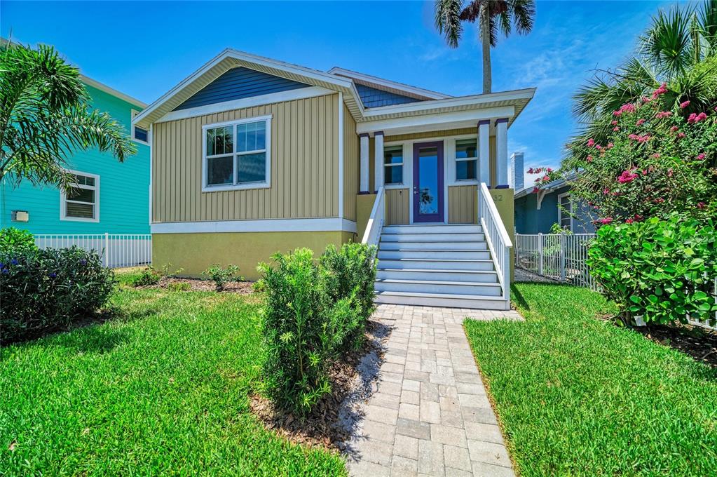 A tan house with a blue gable, white stairs, and a paved walkway leading inside — 632 VIRGINIA DRIVE, BRADENTON, FL