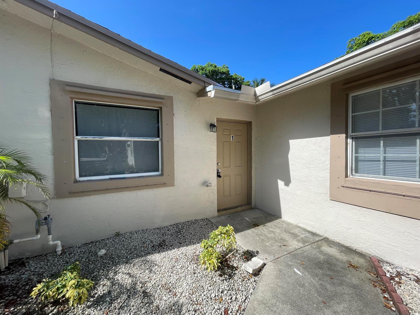 An exterior view of a building entrance with a tan door labeled number one — 216 NW 12th # 1, Pompano Beach FL 33060, POMPANO BEACH, FL