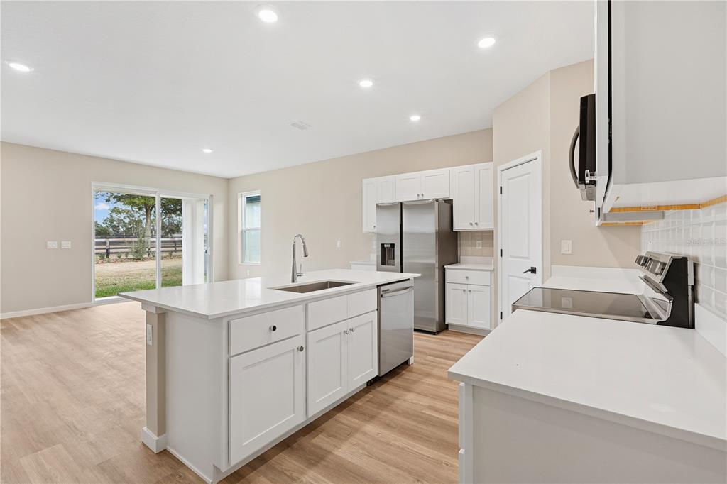 A modern kitchen features white cabinets, stainless steel appliances, and a central island with seating — 4441 NW 37TH STREET ROAD, OCALA, FL