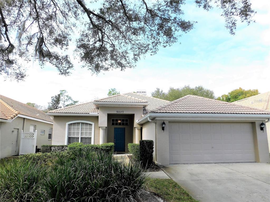 A single-story house with a beige stucco exterior, a two-car garage, and a tiled roof — 5107 PINNACLE DRIVE, OLDSMAR, FL