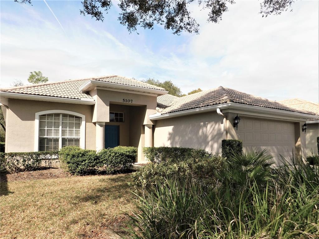 A single-story suburban house with a tan stucco exterior, tile roof, and attached two-car garage — 5107 PINNACLE DRIVE, OLDSMAR, FL