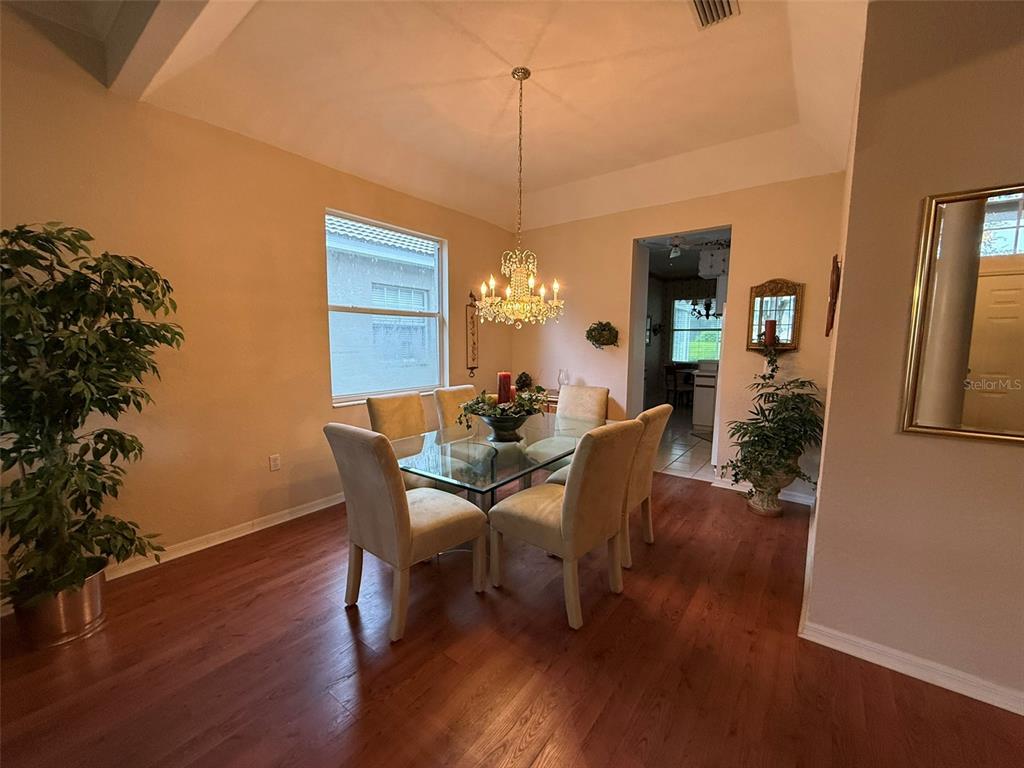A dining room features a glass-topped table, six upholstered chairs, and a crystal chandelier — 5107 PINNACLE DRIVE, OLDSMAR, FL