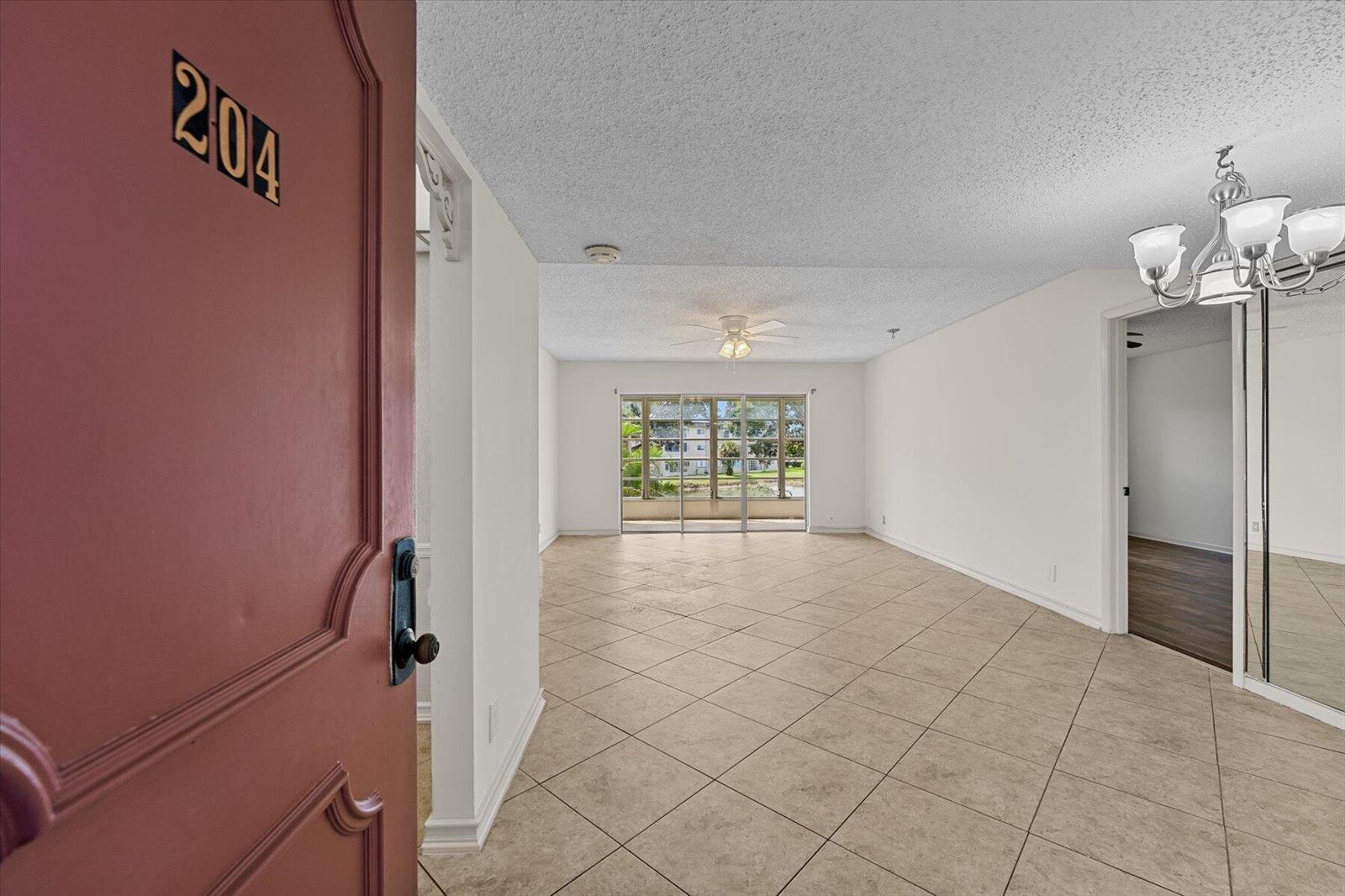 An open doorway reveals a tiled living area with a ceiling fan and large windows — 719 Lori Drive # 204, Palm Springs FL 33461, PALM SPRINGS, FL