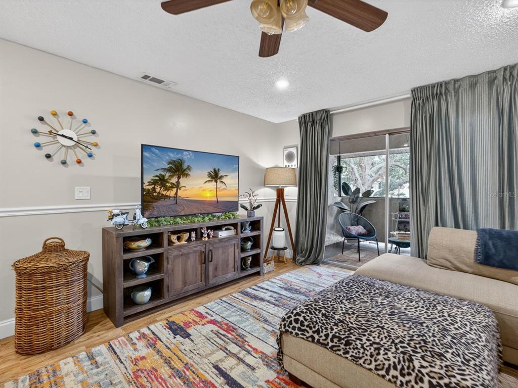 A living room features a wooden media console, a patterned rug, and a sliding glass door — 6110 CURRY FORD ROAD UNIT 219, ORLANDO, FL