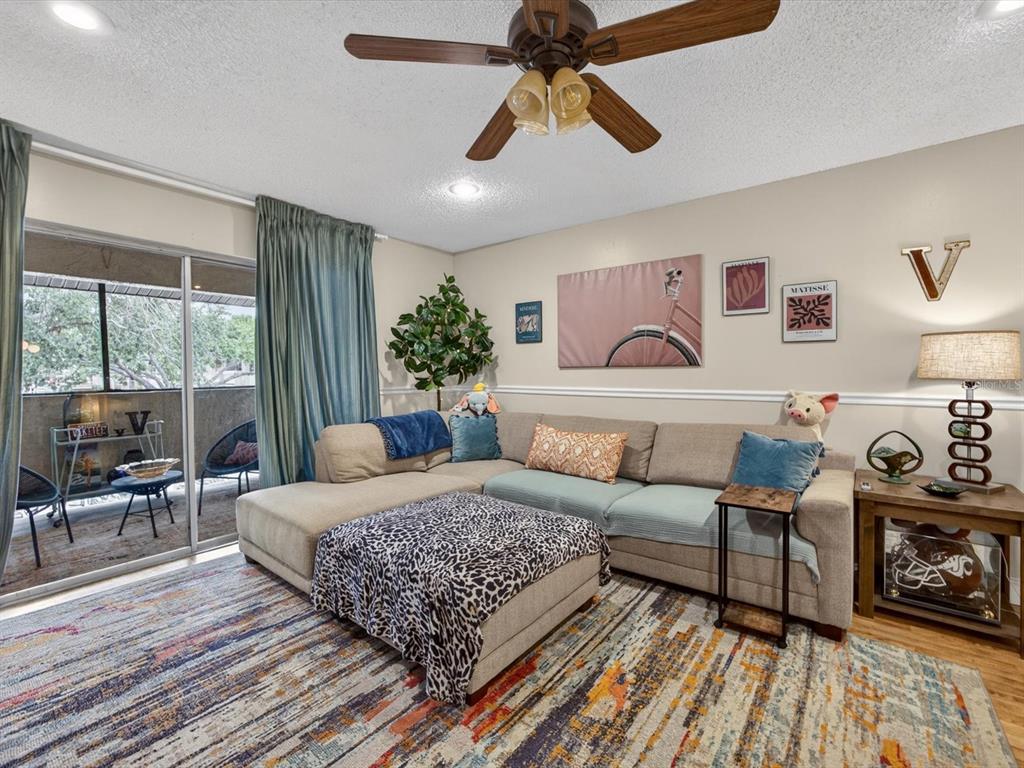 A living room features a sectional sofa, a patterned rug, and a sliding glass door — 6110 CURRY FORD ROAD UNIT 219, ORLANDO, FL