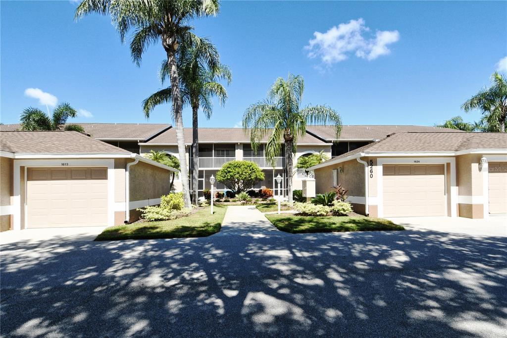 A two-story residential building features two garages, a central walkway, and palm trees — 5260 HYLAND HILLS AVENUE UNIT 1616, SARASOTA, FL