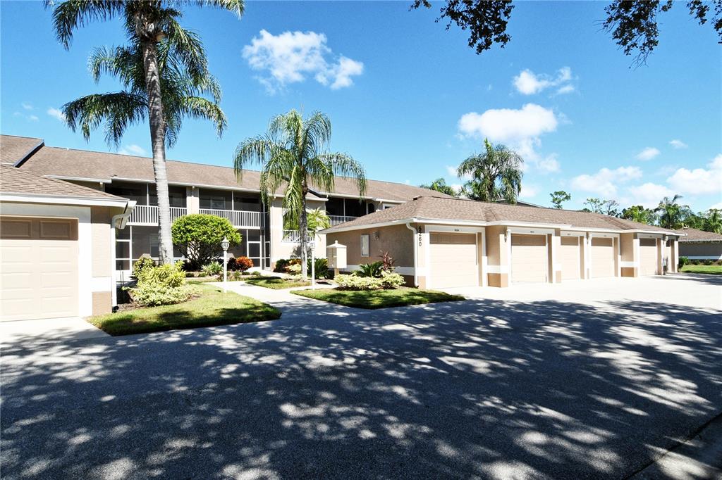 A multi-unit residential building with tan stucco walls, brown shingle roofs, and attached garages — 5260 HYLAND HILLS AVENUE UNIT 1616, SARASOTA, FL