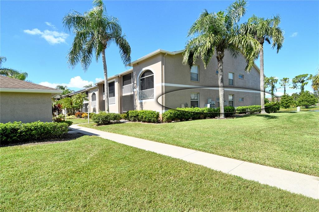 The exterior of a multi-story apartment building features a sidewalk, palm trees, and landscaping — 5260 HYLAND HILLS AVENUE UNIT 1616, SARASOTA, FL