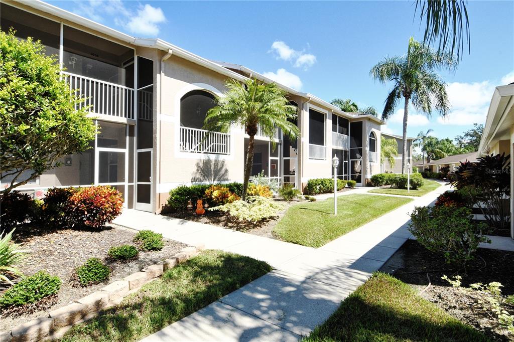 A sidewalk leads past a two-story apartment building with screened balconies and landscaped grounds — 5260 HYLAND HILLS AVENUE UNIT 1616, SARASOTA, FL