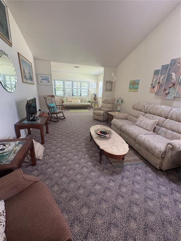 A living room features patterned carpeting, a beige sofa, a recliner, and a rocking chair — 22 BRISTOL DRIVE, PALM COAST, FL